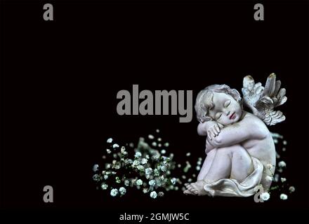 Condolence card with sleeping angel and white flowers isolated on black background Stock Photo