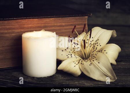 Condolence card with white candle, lily flower and closed book Stock Photo
