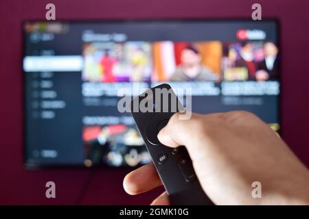 Hand Holding Remote Control and Changing Channel Stock Photo