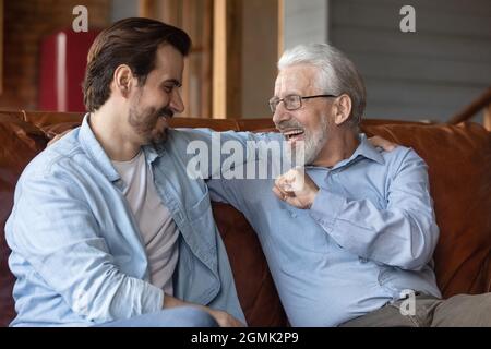 Excited mature father with grown-up son talking, having fun Stock Photo