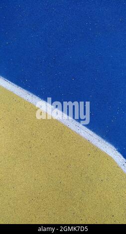 Texture of the painted coating of the sports ground - yellow, blue, white Stock Photo