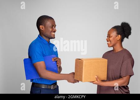 african woman shakes had with a delivery worker after receiving a package Stock Photo