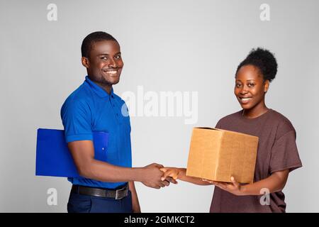 black woman shakes had with a delivery worker after receiving a package Stock Photo