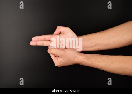 man making gun gesture on dark background Stock Photo