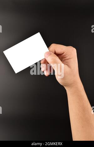hand holding blank visiting card over dark background, white card for message and advertising text Stock Photo