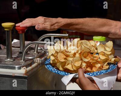 A customer adds tomato catsup to a plate of ribbon fries purchased from a food vendor at the annual Fiesta de Santa Fe in Santa Fe, New Mexico. Stock Photo