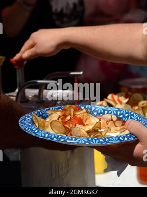 A customer adds tomato catsup to a plate of ribbon fries purchased from a food vendor at the annual Fiesta de Santa Fe in Santa Fe, New Mexico. Stock Photo
