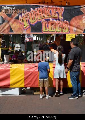 Customers purchase smoked turkey legs from a food vendor at the annual Fiesta de Santa Fe in Santa Fe, New Mexico. Stock Photo