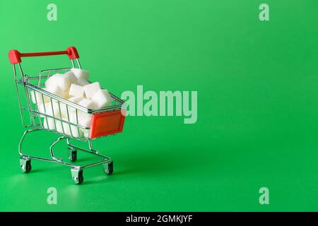 Shopping cart with sweet sugar on color background Stock Photo