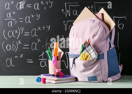 School backpack and stationery on table in classroom Stock Photo