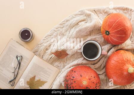 A cup of espresso coffee on a table with pumpkins, autumn leaves, book and eyeglasses on a knitted sweater. Autumn concept, top view Stock Photo