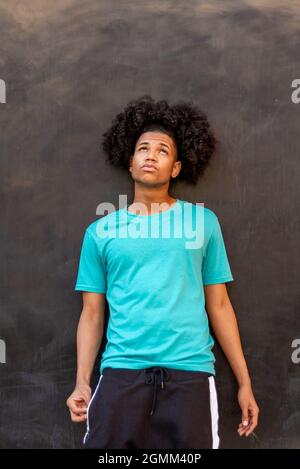 Portrait of young afro latin man against a black wall Stock Photo