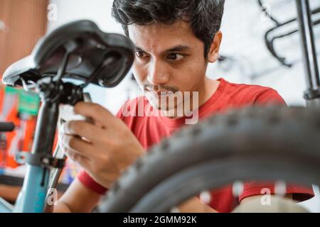 close up of a handsome mechanic tightening saddle screws using a wrench Stock Photo