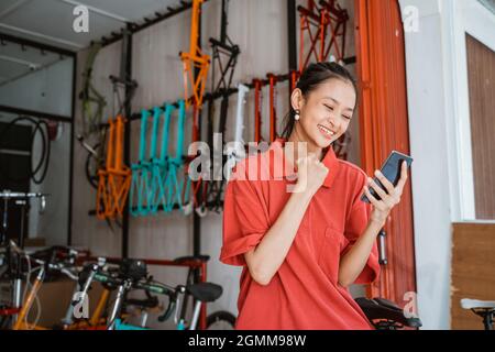 excited young woman with hands clenched when looking on smartphone screen Stock Photo