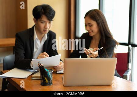 Cheerful young colleagues working together. young businesswoman in wheelchair working with coworker in office Stock Photo