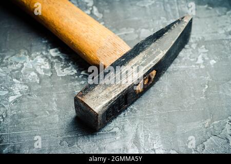 Old hammer on the gray concrete background. Macro shot. Selective focus. Shallow depth of field. Stock Photo
