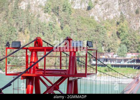 A suspension bridge over a wide river in the mountains. Safe crossing of the bridge from one bank to the other. Stock Photo