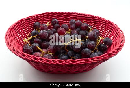 Fresh Red Grapes in a red basket isolated on white background. Stock Photo
