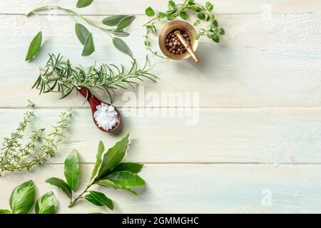 Fresh herbs, shot from above on a wooden background with salt and pepper, with copy space. Rosemary, bay leaf, thyme, sage and other aromatic plants Stock Photo