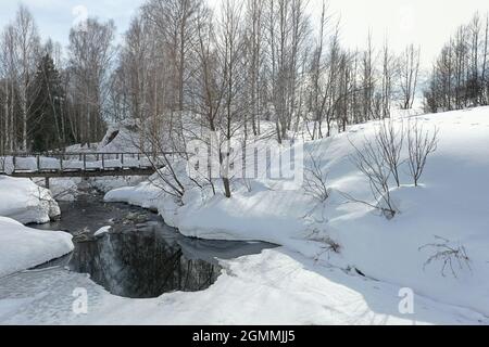 snowy wooden bridge over small river in Siberia Stock Photo