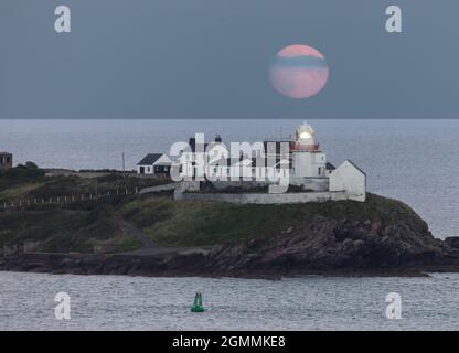 Roches Point, Cork, Ireland. 19th September, 2021. September's Harvest Moon rises over the Roches Point lighthouse, Co. Cork, Ireland.- Picture; David Creedon / Alamy Live News Stock Photo