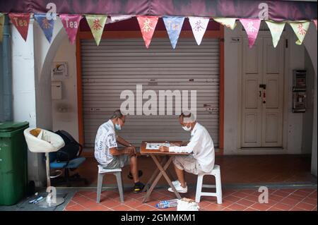 15.09.2021, Singapore, Republic of Singapore, Asia - Two elderly men wearing protective face masks play Chinese chess (Xiangqi) in Chinatown. Stock Photo