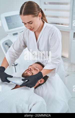 Certified cosmetologist performing a non-invasive skin tightening procedure Stock Photo