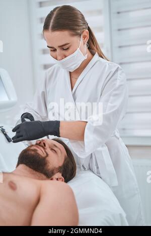 Professional cosmetologist performing a non-invasive skin tightening Stock Photo