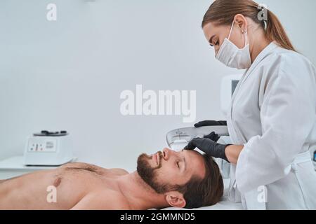 Female dermatologist carrying out the non-surgical ultrasonic skin tightening Stock Photo