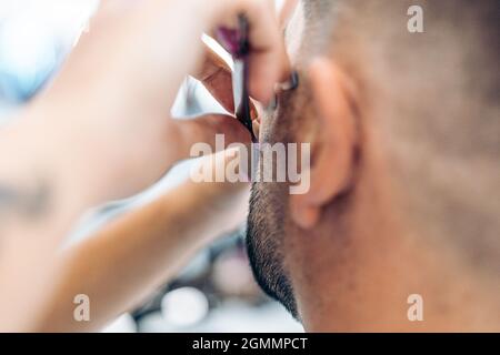 Cropped unrecognizable male barber with razor and sharpening