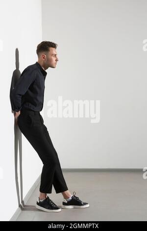 Thoughtful young man leaning against wall Stock Photo