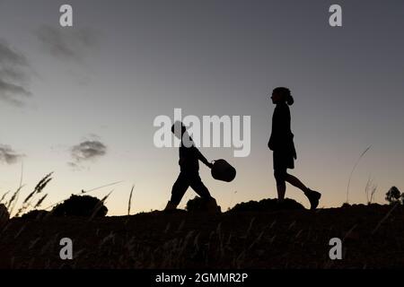 Silhouette mother and son walking against dusk sky Stock Photo