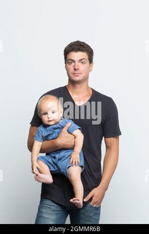 Portrait confident father holding baby son on white background Stock Photo