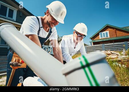 Construction workers in helmets leaning over table Stock Photo