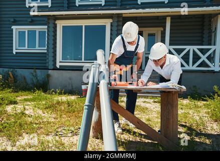 Worker in overalls putting spirit level on drawings Stock Photo