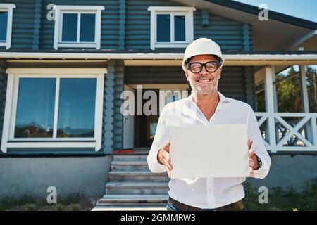 Cheerful construction specialist showing paper to camera Stock Photo