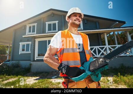 Man posing for photo with chainsaw near house Stock Photo