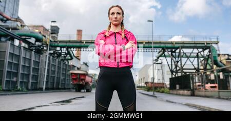 Sportswoman with crossed arms posing in front of a factory Stock Photo