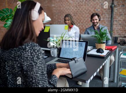Young and old architects sitting and working at desk in office, cooperation and coworking concept. Stock Photo