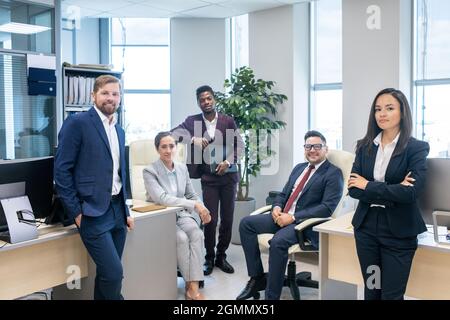 Large group of young successful intercultural white collar workers in open space office Stock Photo