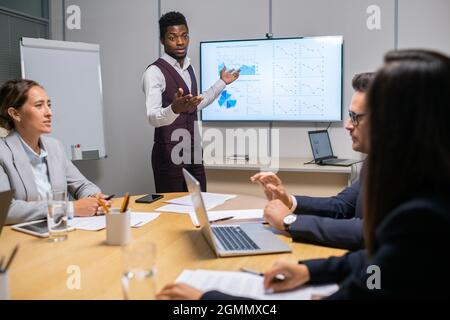 Young confident speaker or coach making report in front of audience at meeting or seminar Stock Photo