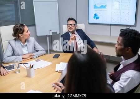 Mature business coach talking to young managers at seminar or training Stock Photo