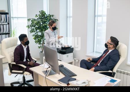 Young intercultural employees discussing working points with their boss in his office Stock Photo