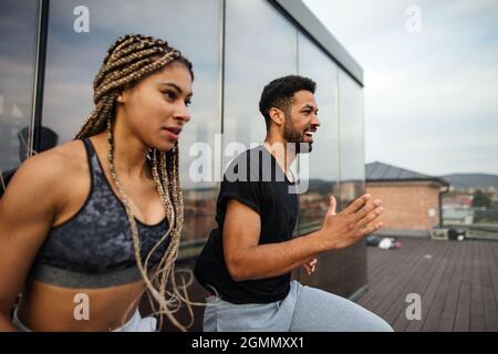 Side view of young couple doing warm up exercise outdoors on terrace, sport and healthy lifestyle concept. Stock Photo