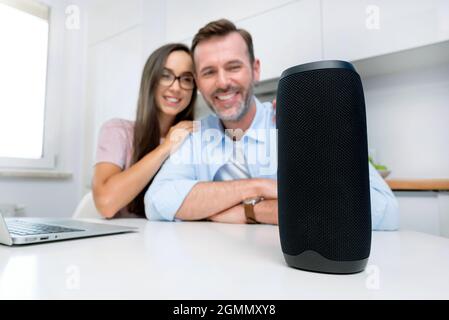 Couple using smart speaker, smart home system appliance, modern assistant Stock Photo