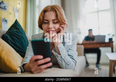 Young couple at home using digital divices, smartphone and laptop, social networks concept. Stock Photo