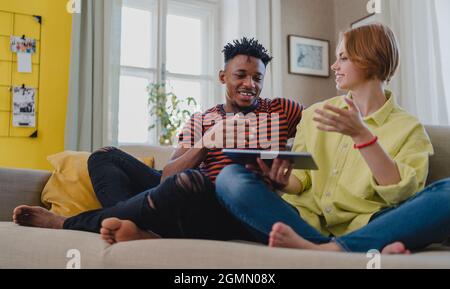 Young mixed couple using tablet, having fun at home, checking social networks together. Stock Photo