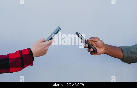 Close up of young mixed couple hands using smartphones on white background Stock Photo