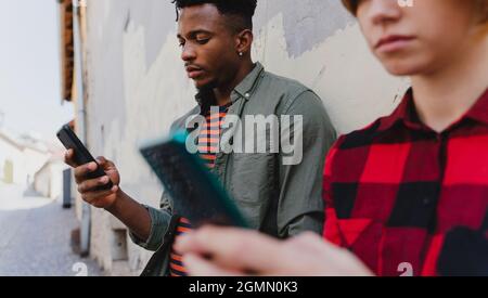 Young mixed couple using smartphones outdoors in town. Stock Photo