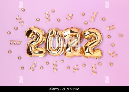 2022 gold inflatable balloons and confetti on a purple background. Holidays concept. Stock Photo